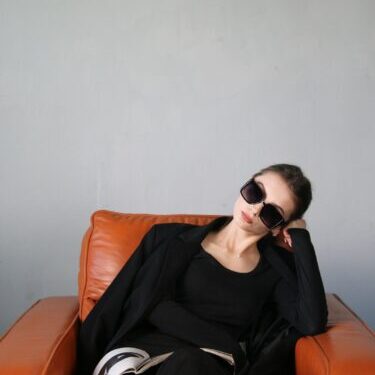 Photo by Lida R a woman sitting on top of a brown couch
