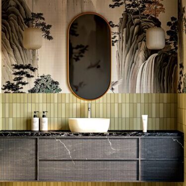 Photo by Ela De Pure A bathroom vanity with a white sink, marble countertop, and landscape wallpaper