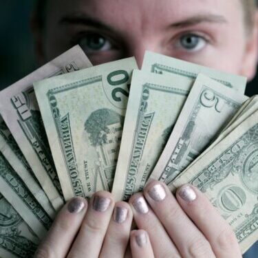 person holding fan of U.S. dollars banknote